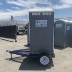 side view of portable toilet trailer in yard